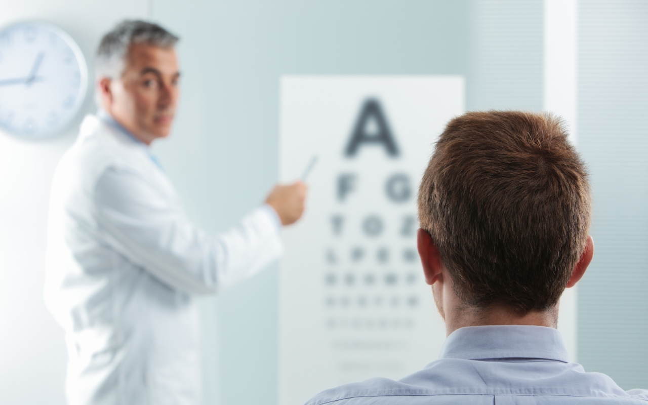 Optometrist and patient, doctor pointing at eye chart